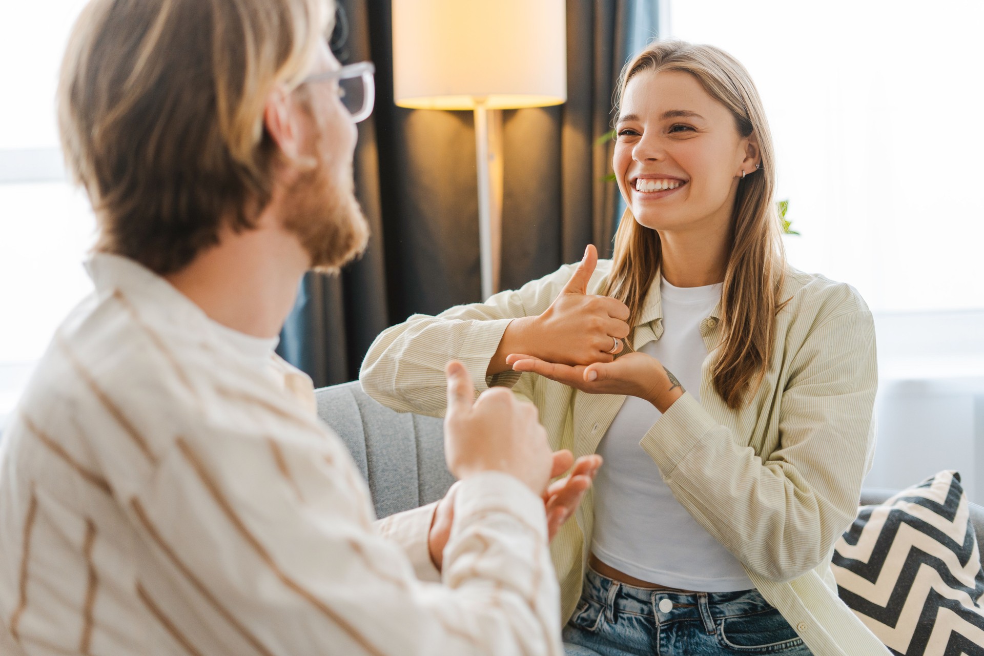 Young woman smiling and gesturing while using sign language with therapist